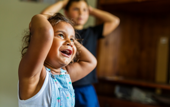 Two smiling children with their hands on their head